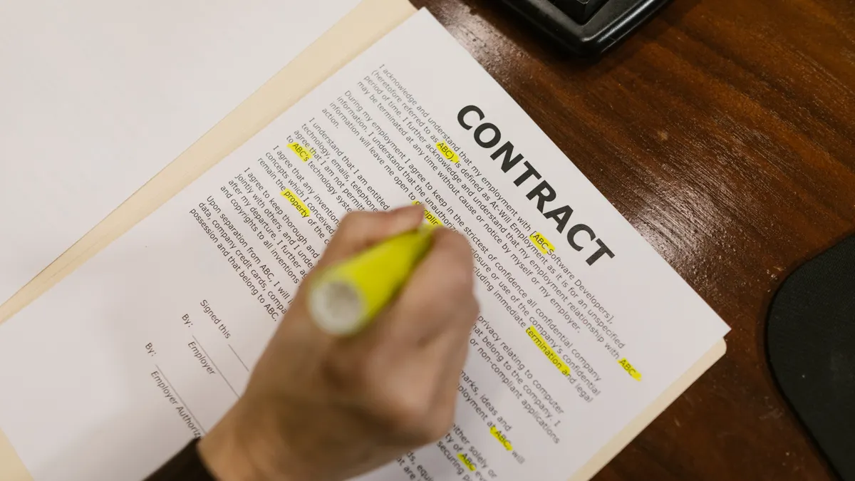 person highlighting a contract at a desk